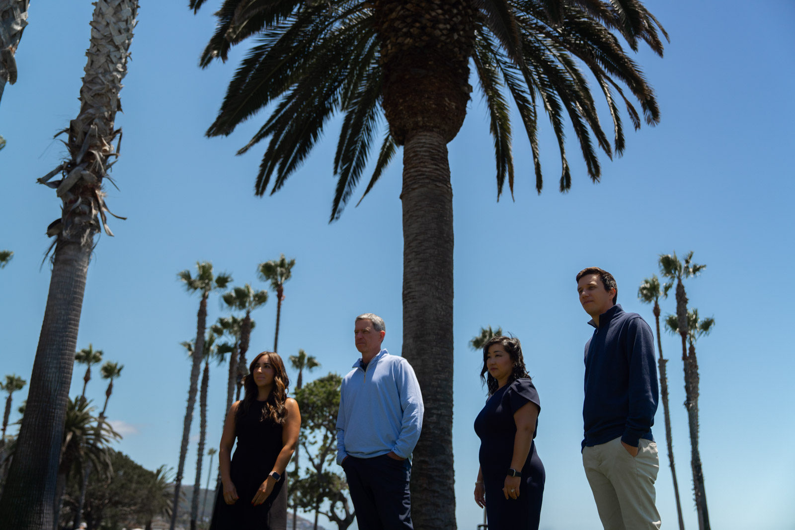 Scott Sargent, CFP, CMFC, Colten Franco, MS, CFP, ChFC, founders and financial advisors at Three Points Wealth Planners in Dana Point California, pose under a palm tree in Orange County, near their office, with the rest of the team.